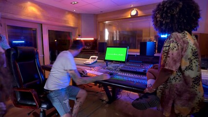 Music producer working with singer in recording studio with green screen