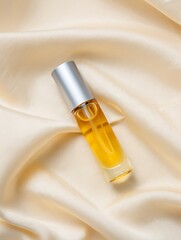 A high end luxury beauty product with golden liquid inside a clear glass bottle with a silver cap on a silky beige background