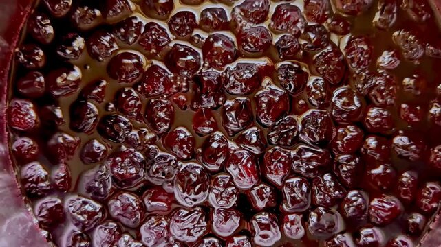 Slow motion shot of ripe red cherries boiling for homemade jam. Natural fruit, sugar, steam, and heat in a rustic kitchen environment.