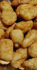 Close up macro view of many crispy golden brown potato tots tater tots
