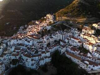 An aerial view captures the dense cluster of whitewashed houses with terracotta roofs, built into...
