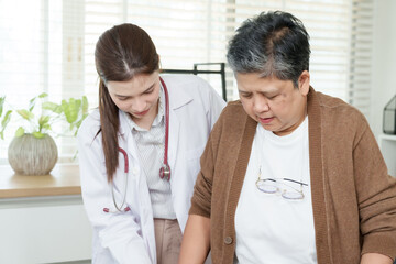 Senior asian woman with joint issues walks slowly using walker assisted by orthopedic doctor during...