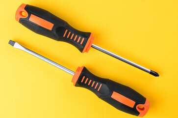 Phillips and flathead screwdrivers metal hand tools on bright yellow background top view