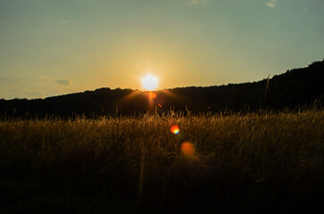 Sunset sun rays shining through dark landscape with little sky peaceful dramatic view