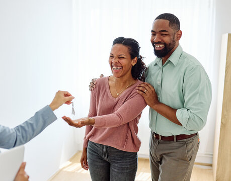 Young black couple receiving keys of new apartment from their real estate agent, standing in the new home