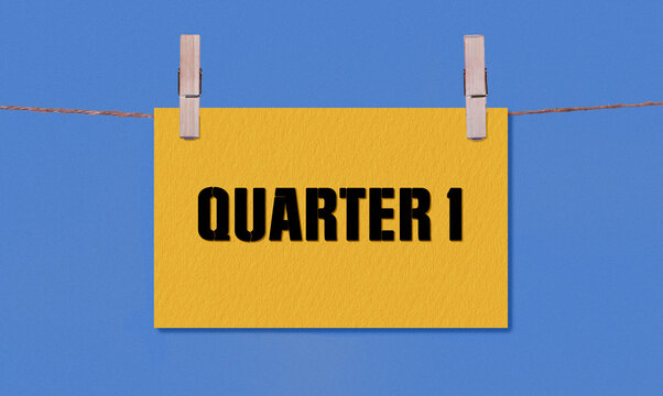 QUARTER 1 Symbol. Concept words QUARTER 1 on Yellow Rectangle Paper Hanging on a Wooden Clothespin Blue Background. Business QUARTER 1 Concept with Copy Space