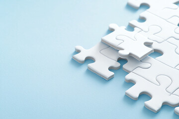 Obraz premium White puzzle pieces on blue background create serene and calming atmosphere, inviting creativity and problem solving. close up view highlights smooth texture and clean lines of pieces