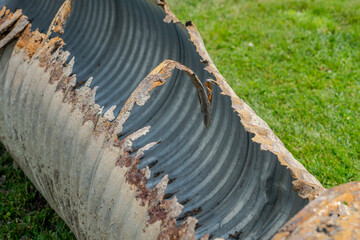 Infrastructure photo of rusted out corrugated metal pipe, CMP, drainage culvert, that has been removed from the ground and being replaced with a new pipe.
