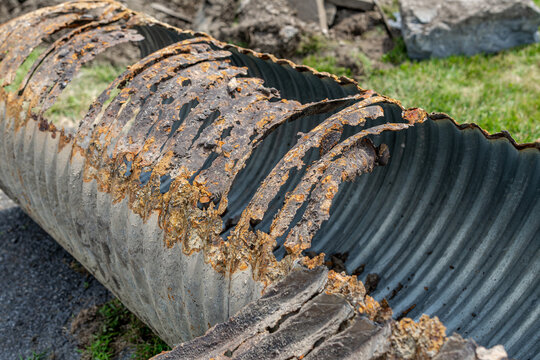 Infrastructure photo of rusted out corrugated metal pipe, CMP, drainage culvert, that has been removed from the ground and being replaced with a new pipe.