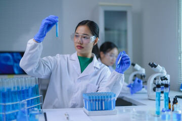 Asian scientists working with test tubes and microscopes, conducting experiments and research in a...