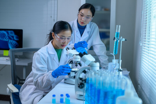 Two scientists analyzing samples under a microscope