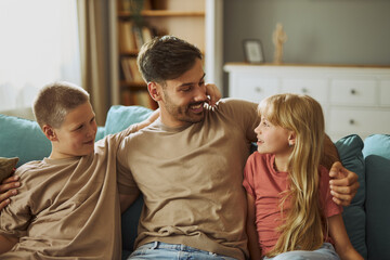Happy single  father communicating with his small children in the living room.