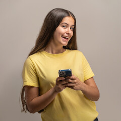 A happy young student listening to music with red headphones and holding a smartphone.