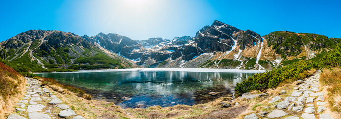 Tatra Mountains panorama with Czarny Staw Gąsienicowy, Orla Perć ridge, hiking trail, alpine lake, Kozi Wierch, spring landscape, snow, and clear blue sky in Poland. © Piotr Wojtkowski