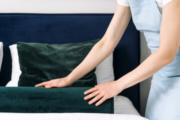 Neatly arranging bedding in a stylish hotel room to enhance guest comfort