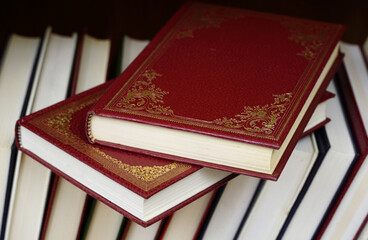 Two red hardcover books on the top of the other books on the book shelf