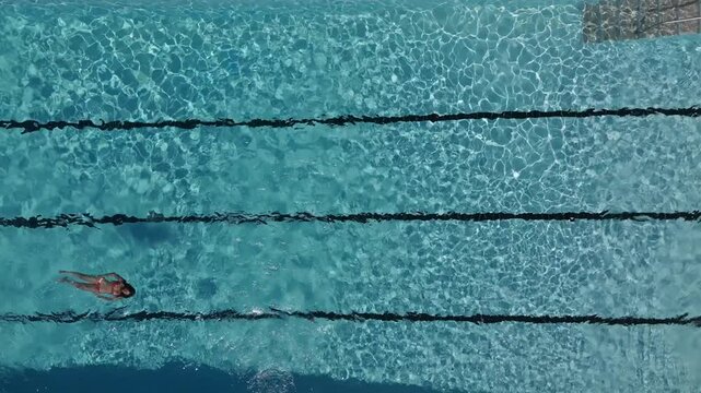 Woman swimming backstroke in pool from above