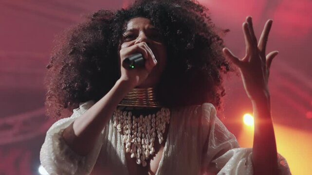 Afro style charismatic performer singing passionately on stage, captivating the audience with her energy emotion and talent, slow motion
