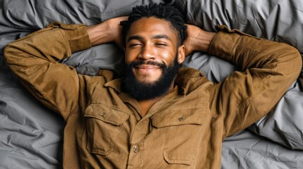 Obraz premium A man with a beard relaxing comfortably on a bed with gray sheets and pillows