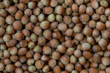 A collection of hazelnuts sits on a dark surface, showcasing their textured shells. This setting provides empty space for potential text or design additions, enhancing visual appeal.