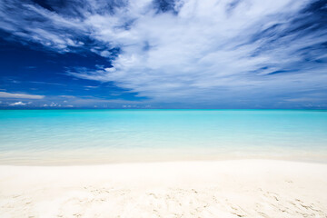 Obraz premium Serene tropical beach with turquoise water and wispy clouds