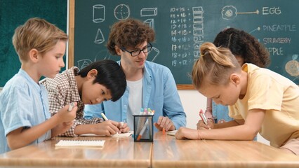 Smart teacher explain idea while diverse children drawing mind map while group of diverse student...