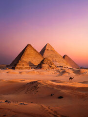 Naklejka premium Iconic Ancient Pyramids with Camel in the Distance at Sunset with Rocky Desert Foreground