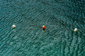 Colorful buoys floating on calm water with ripples in a serene coastal environment