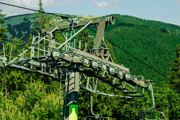 Ski lift mechanism in mountainous region surrounded by lush greenery during sunny weather