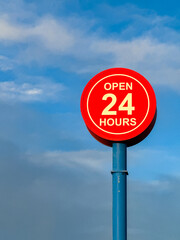 Open 24 hours sign isolated against a blue sky. No people, Copy space.