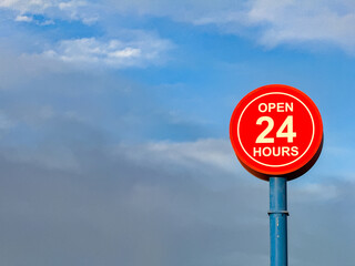 Open 24 hours sign isolated against a blue sky. No people. Copy space.