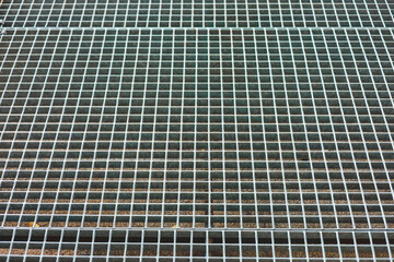 Metal grating surface with squares arranged in a pattern and detail of metallic texture