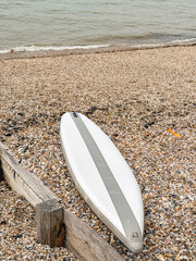 Paddleboard laying on a shale beach. No people.