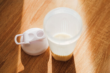 Smoothie protein preparation in a clear cup with lid on a wooden table during morning sunlight