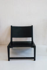 Modern black chair stands alone against a minimalist white backdrop in a bright room