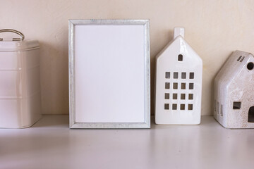 Blank picture mockup frame and decorative ceramic houses on a wooden table