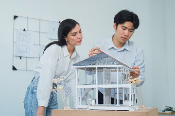 Portrait of cooperative engineer team working together to measure house model by using ruler and...