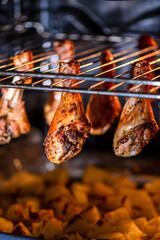 Juicy chicken drumsticks roasting on an oven rack, with golden baked potatoes beneath. Perfectly cooked meal showcasing a delicious combination of flavors and textures