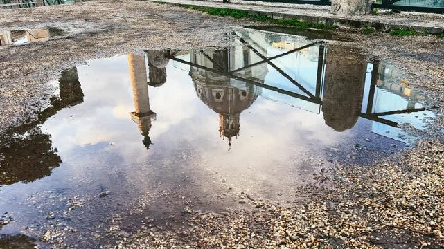 View of a Roman architectural landmark Church Santa Maria Di Loreto reflected in a puddle of water, creating a unique abstract mirror video