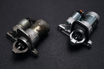 Old used and new automobile starters on dark background comparison