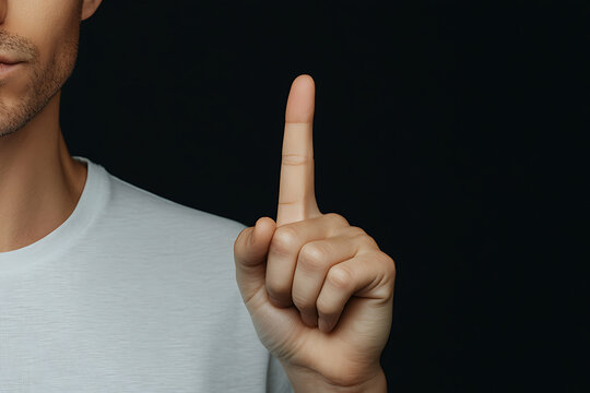 One: A man's hand points upward against a dark background. The index finger is extended, signaling a singular count or concept in the light.