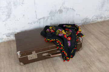 Vintage old classic travel leather suitcase circa 1940-60s with a vintage scarf. Travel luggage concept. Retro brown suitcase on a white wall background.