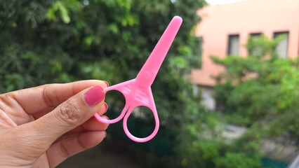 Female holding Pink Plastic Scissor for kids, Stationery item for crafting purpose, easy to cut paper but does not hurt children finger, as it is safe