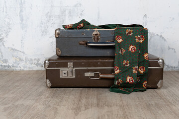 Vintage old classic travel leather suitcase circa 1940-60s with a vintage scarf. Travel luggage concept. Retro brown suitcase on a white wall background.
