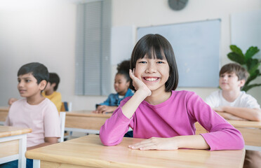 Portrait of little asian pupil smile at desk in classroom at the elementary school. Student girl...