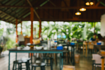 Cozy and Blurred Interior of a Rustic Restaurant Surrounded by Lush Greenery and Natural Light