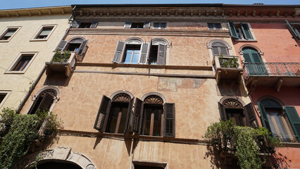 Beautiful traditional Italian building with flowers on balcony of medieval wall, Verona, Italy