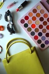 Green bag, various colorful jewelry, sunglasses, hair accessories and colorful make up on white background. Flat lay.