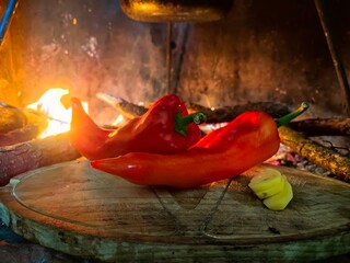 Red paprika on the kitchen board. Red peppers with fire in background