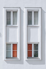 White Minimalist Facade with Four Symmetrical Windows and Red Blinds